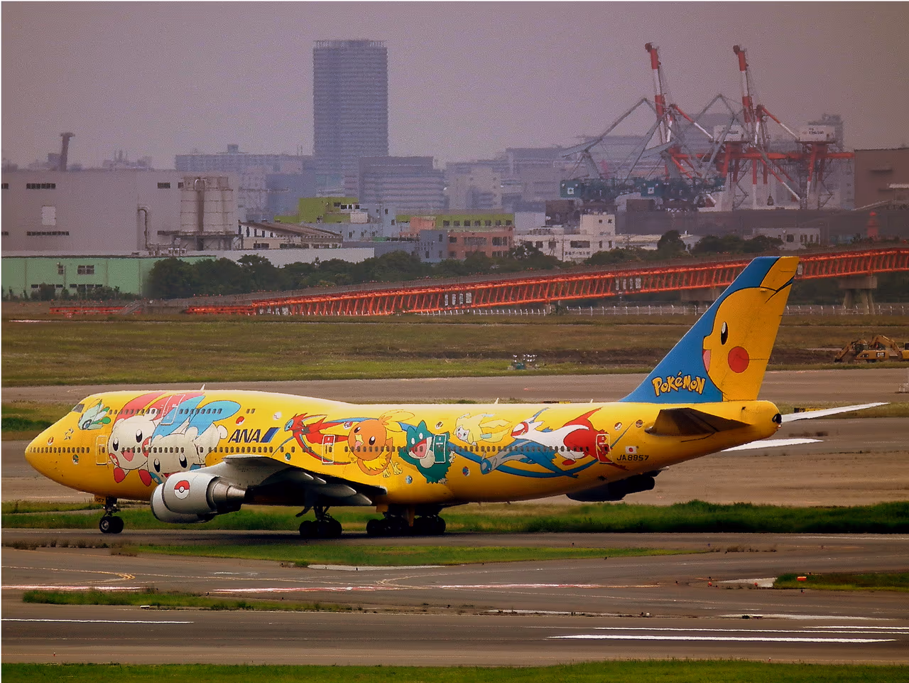An All Nippon Airways Boeing 747-400D in yellow Pokémon livery, with Pikachu painted across the tail and Pokémon along the fuselage, taxiing at Tokyo Haneda