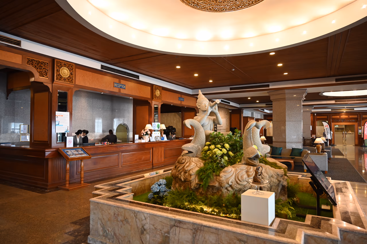 A hotel lobby with a stone fountain and a wood reception desk