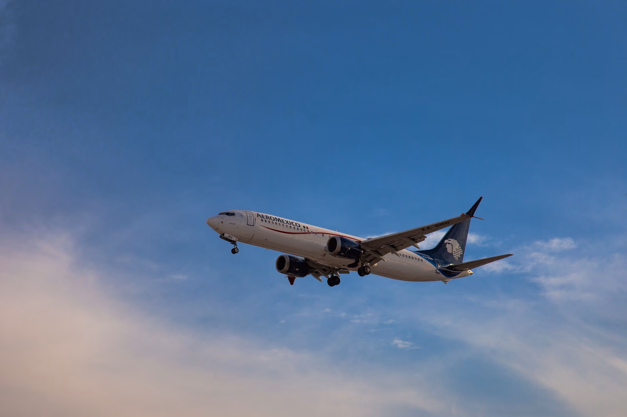 An Aeromexico Boeing 737 in flight against a clear blue sky