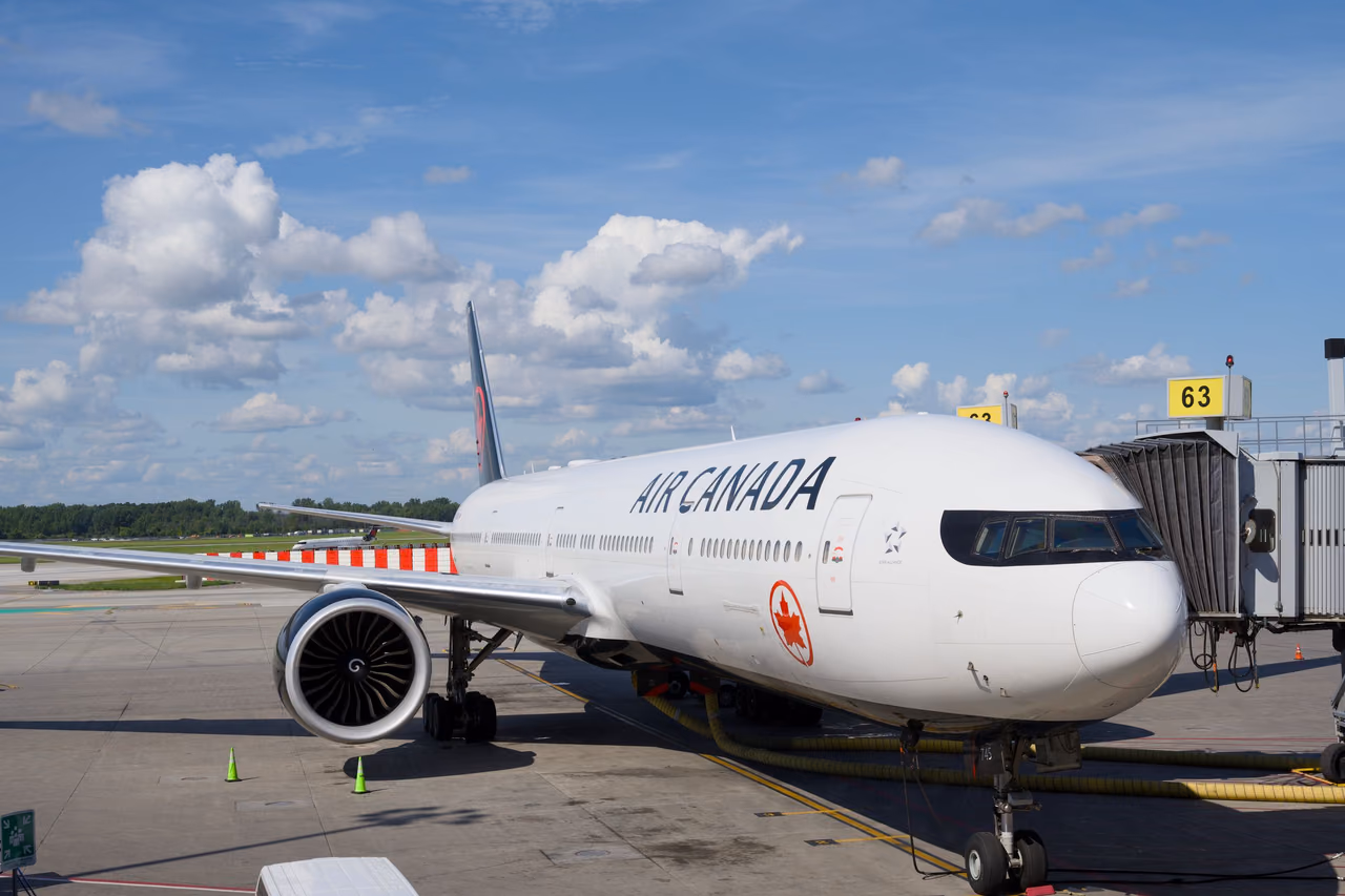 An Air Canada Boeing 777 parked at an airport gate under a clear blue sky