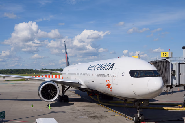 An Air Canada Boeing 777 parked at an airport gate under a clear blue sky
