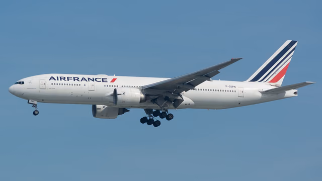 An Air France Boeing 777 in flight against a clear blue sky