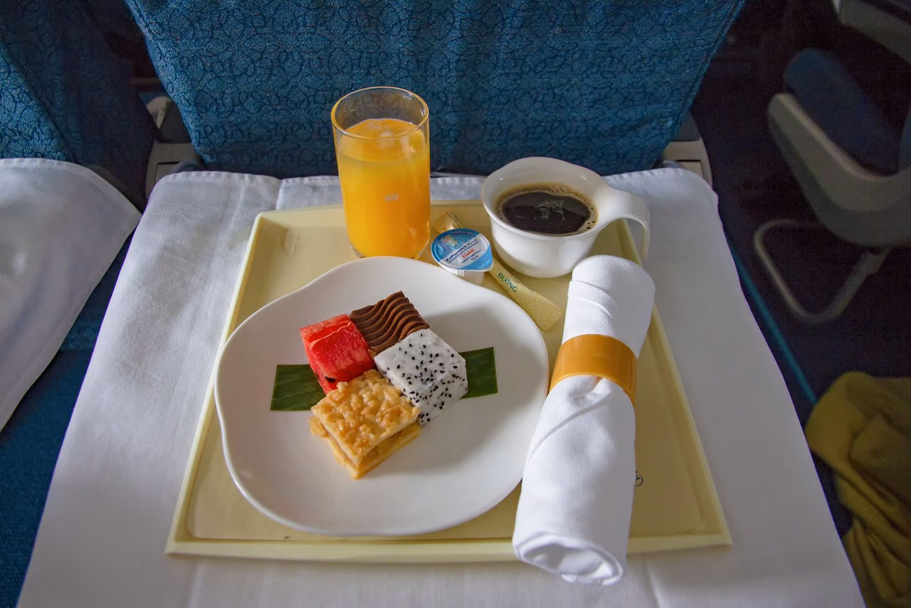 An airline meal tray with a dessert, orange juice and coffee