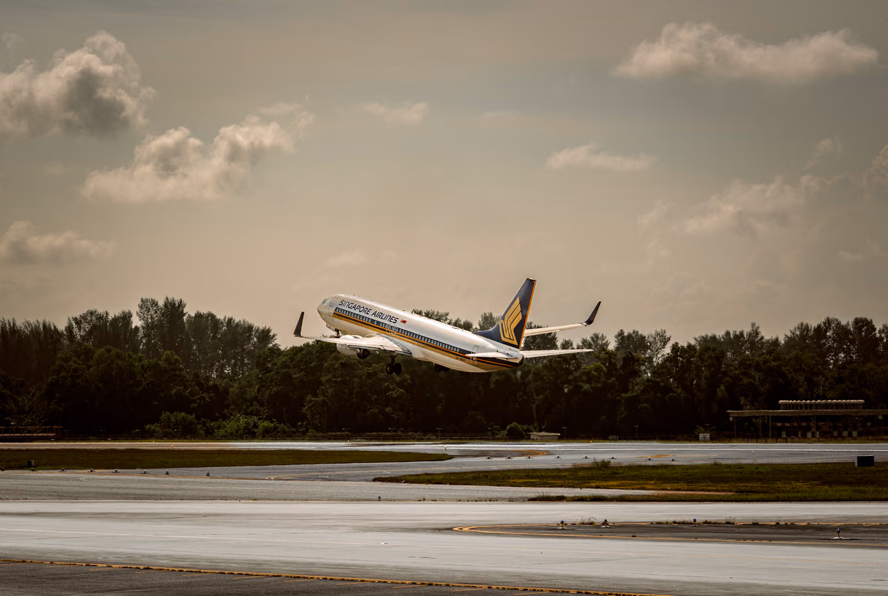 Airliner taking off from an airport runway into a partly cloudy sky