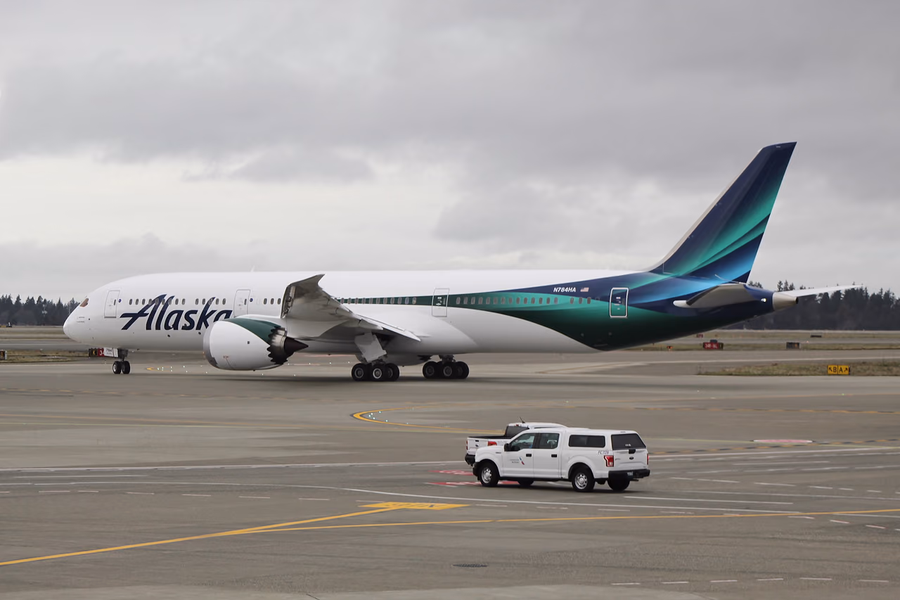 An Alaska Airlines Boeing 787-9 in its global livery taxiing at Seattle-Tacoma International Airport under a gray sky
