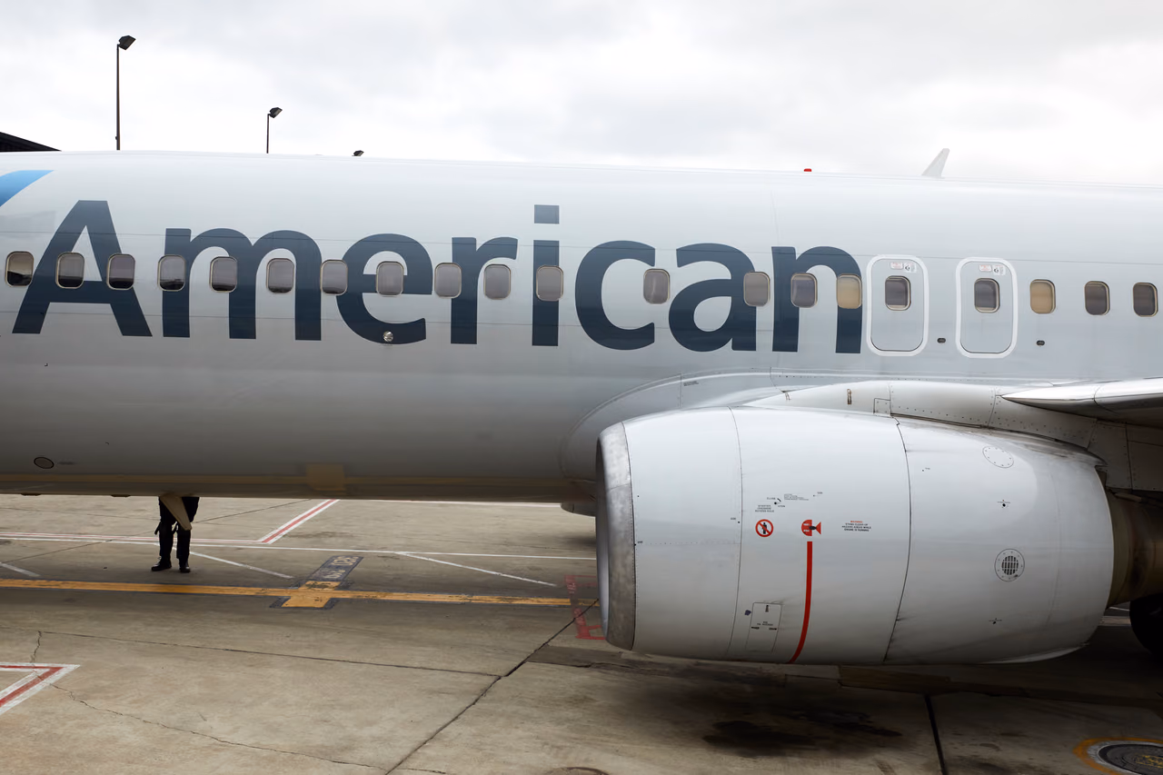 The word American on the side of a Boeing 737 fuselage above its engine, parked on the airport ramp