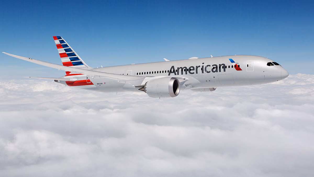 An American Airlines Boeing 787 Dreamliner flying above a layer of white clouds under a blue sky