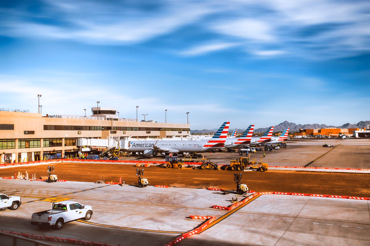 A line of American Airlines jets parked at Phoenix Sky Harbor with mountains behind them