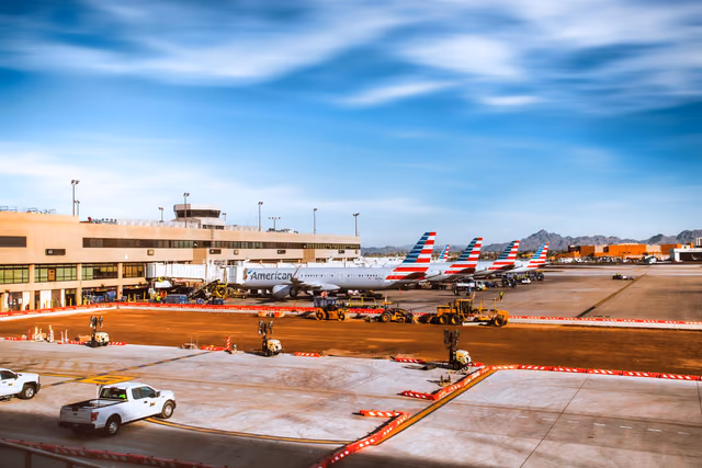 A line of American Airlines jets parked at Phoenix Sky Harbor with mountains behind them