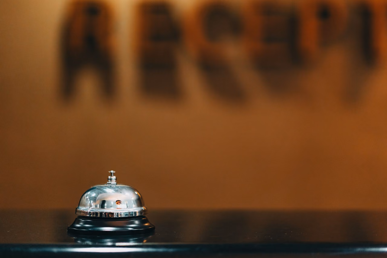 Silver call bell on a dark counter with a blurred reception sign behind it