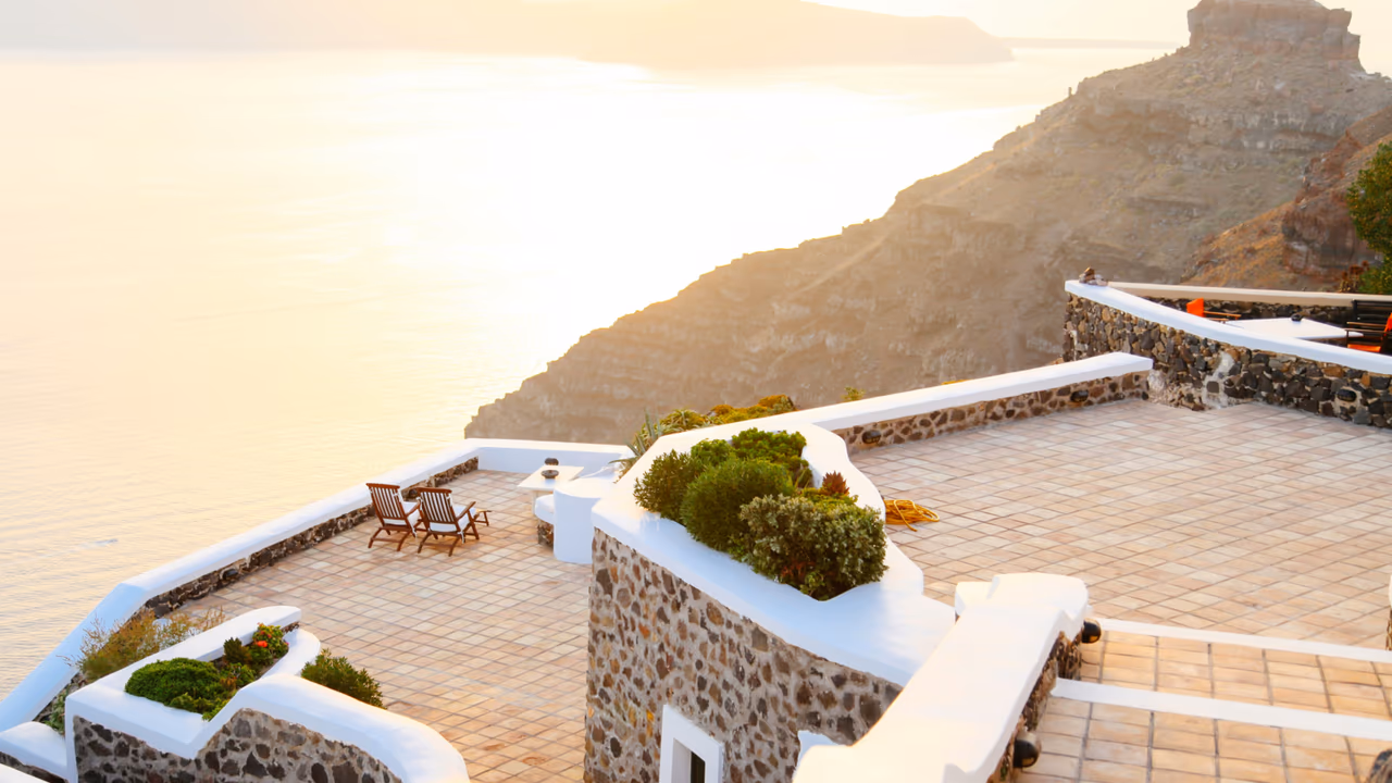Cliffside terrace with chairs overlooking ocean at sunset