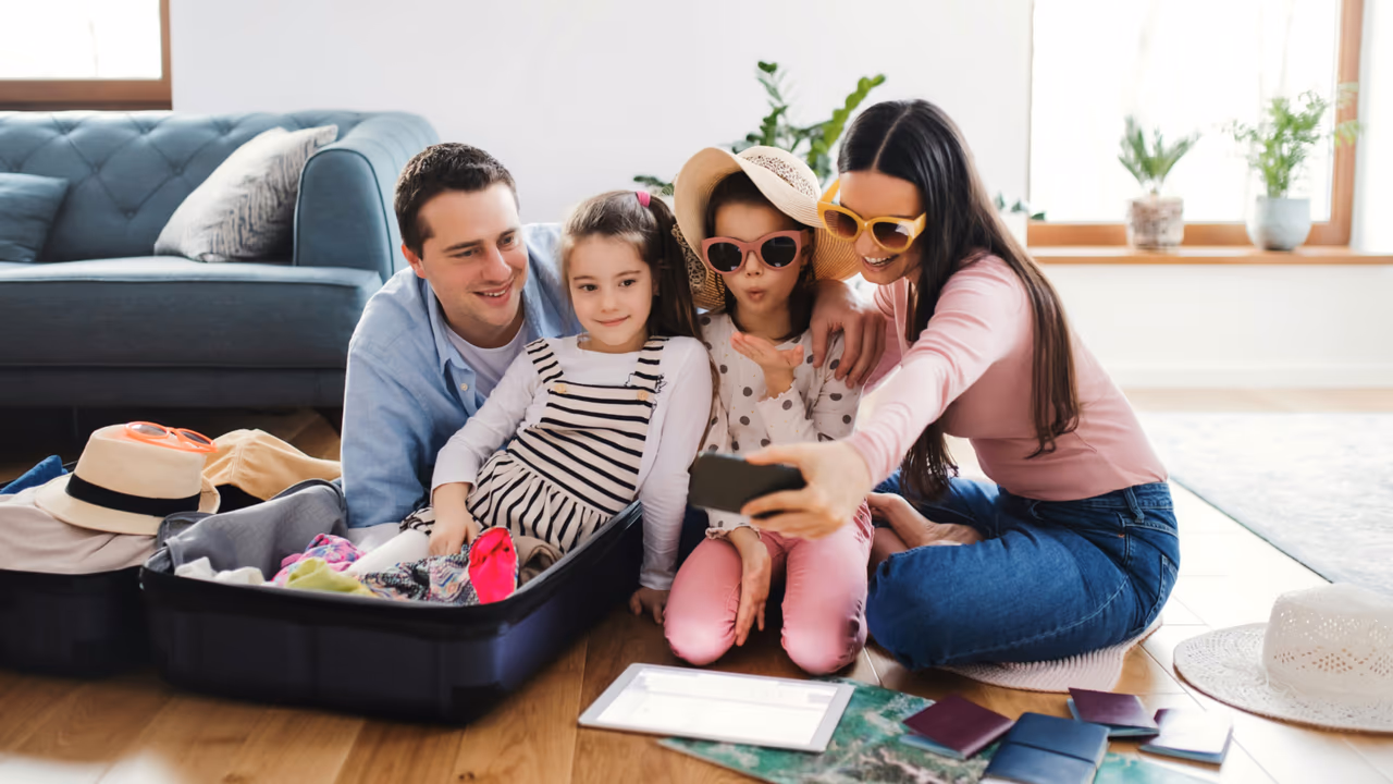 Family taking a travel selfie while packing a suitcase