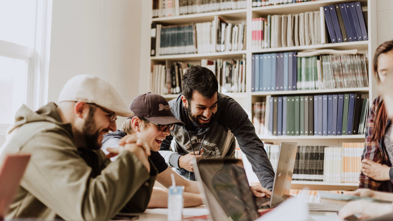 Team laughing together while working on laptops