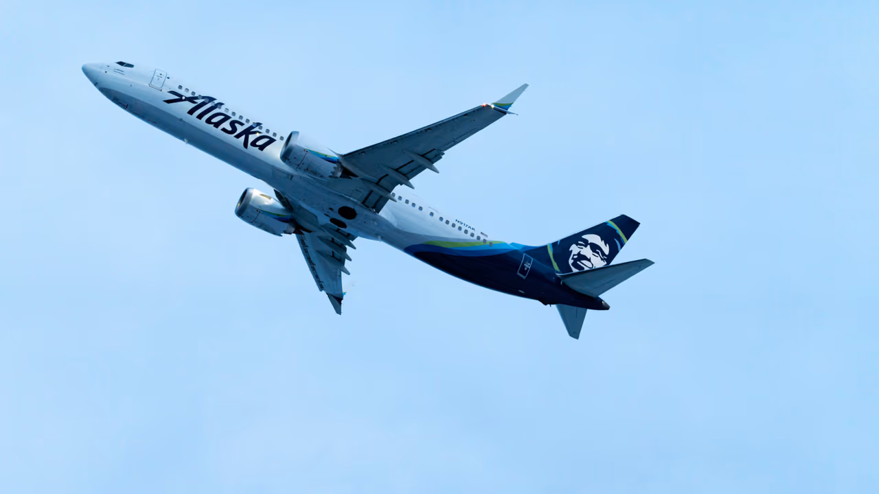Alaska Airlines plane taking off against blue sky