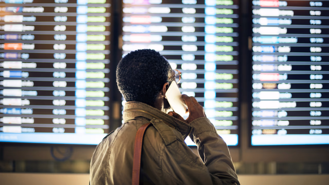 Traveler checking phone at airport departure board