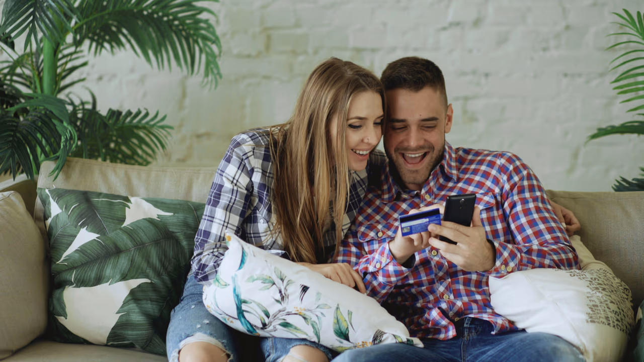 Couple checking a credit card on a smartphone at home