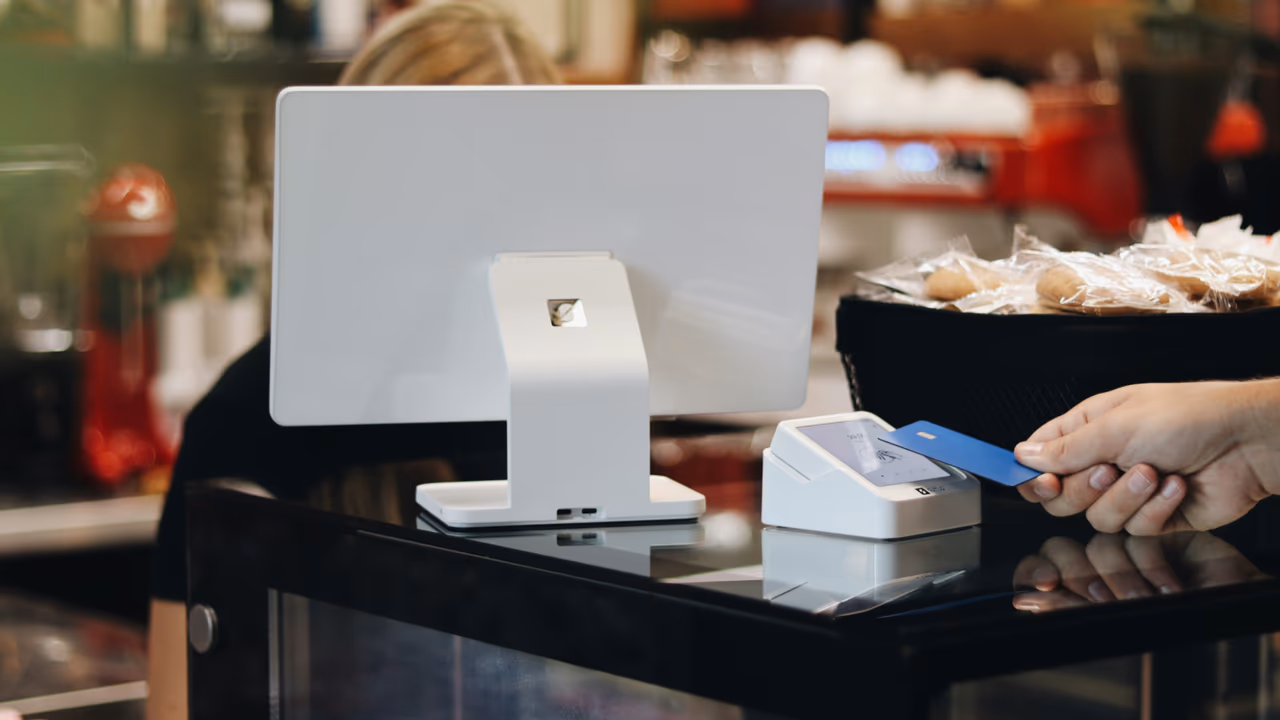 Customer paying with a credit card at a modern point-of-sale terminal in a café