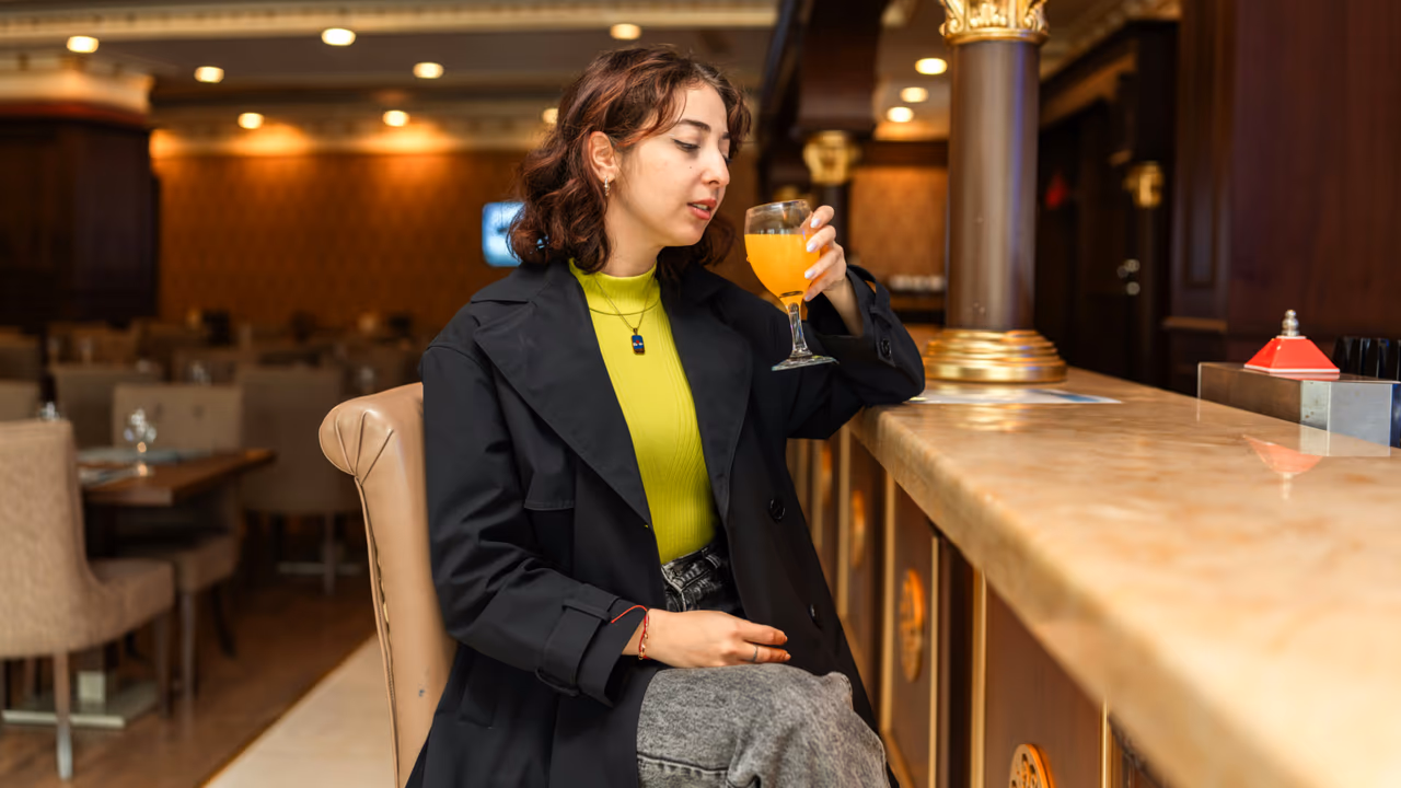 Woman drinking orange cocktail at bar