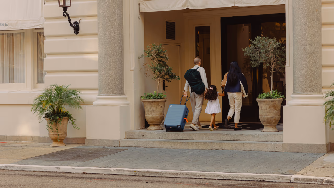 Family entering hotel with luggage.