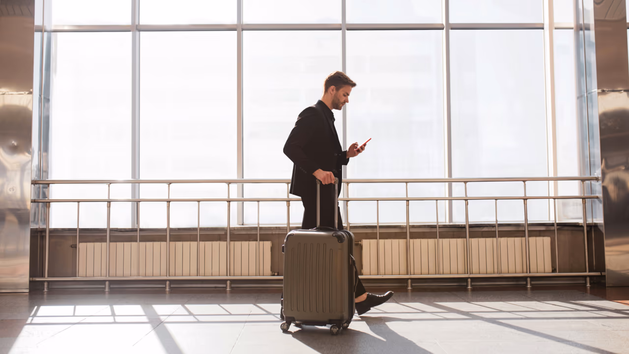 Traveler at airport checking phone with luggage