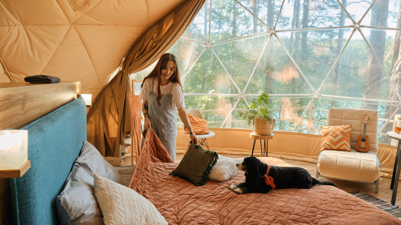 Glamping dome bedroom with woman, dog, and forest view
