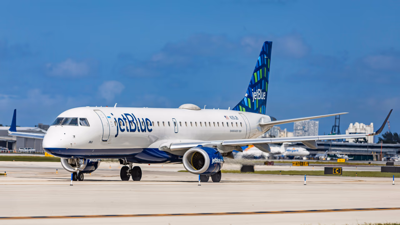 JetBlue aircraft taxiing on airport runway.