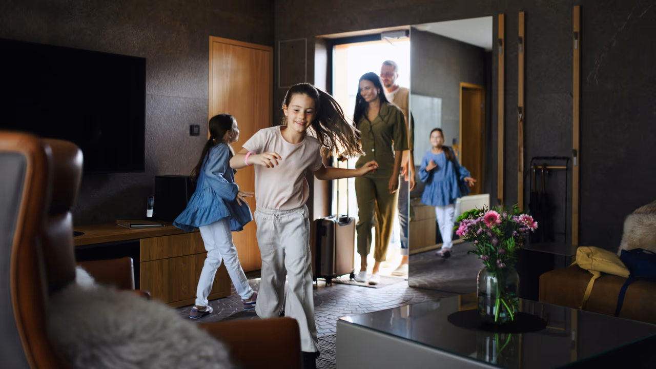 Family entering hotel room with luggage.