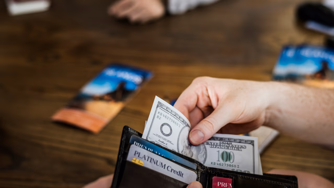 Taking cash from wallet with credit cards on table