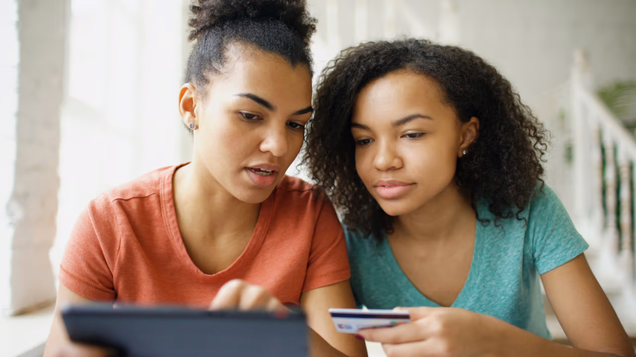 Two women using a tablet and a credit card