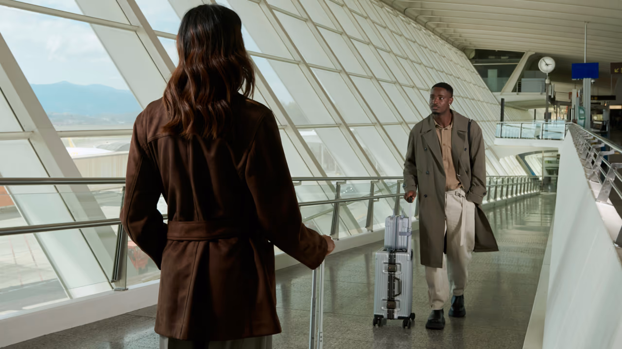 Two travelers with luggage meeting in a modern airport terminal