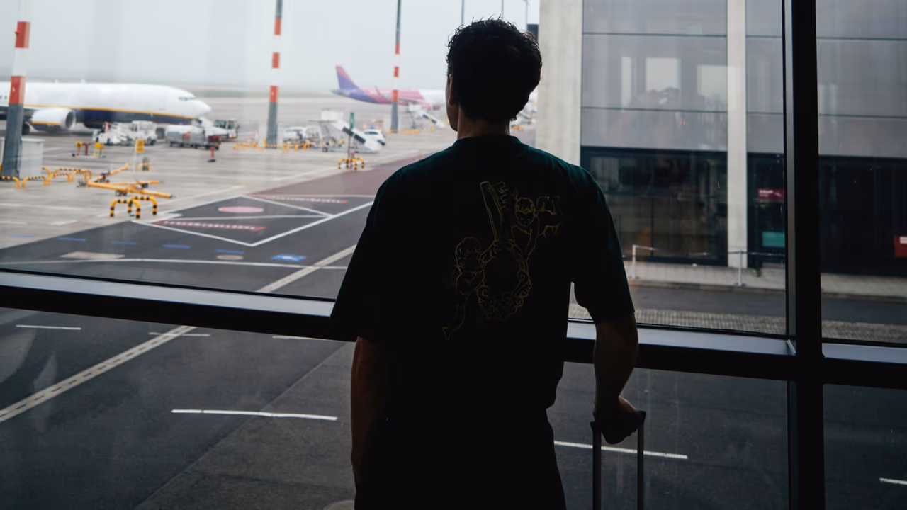 Traveler at airport terminal window viewing planes
