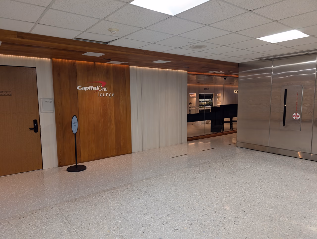 The entrance to the Capital One Lounge at Washington Dulles Airport, with the lounge sign on a wood-paneled wall