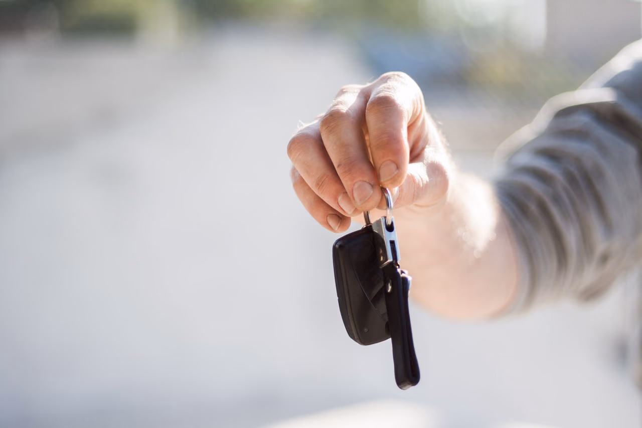 A hand holding out a car key fob, as at a rental car handover