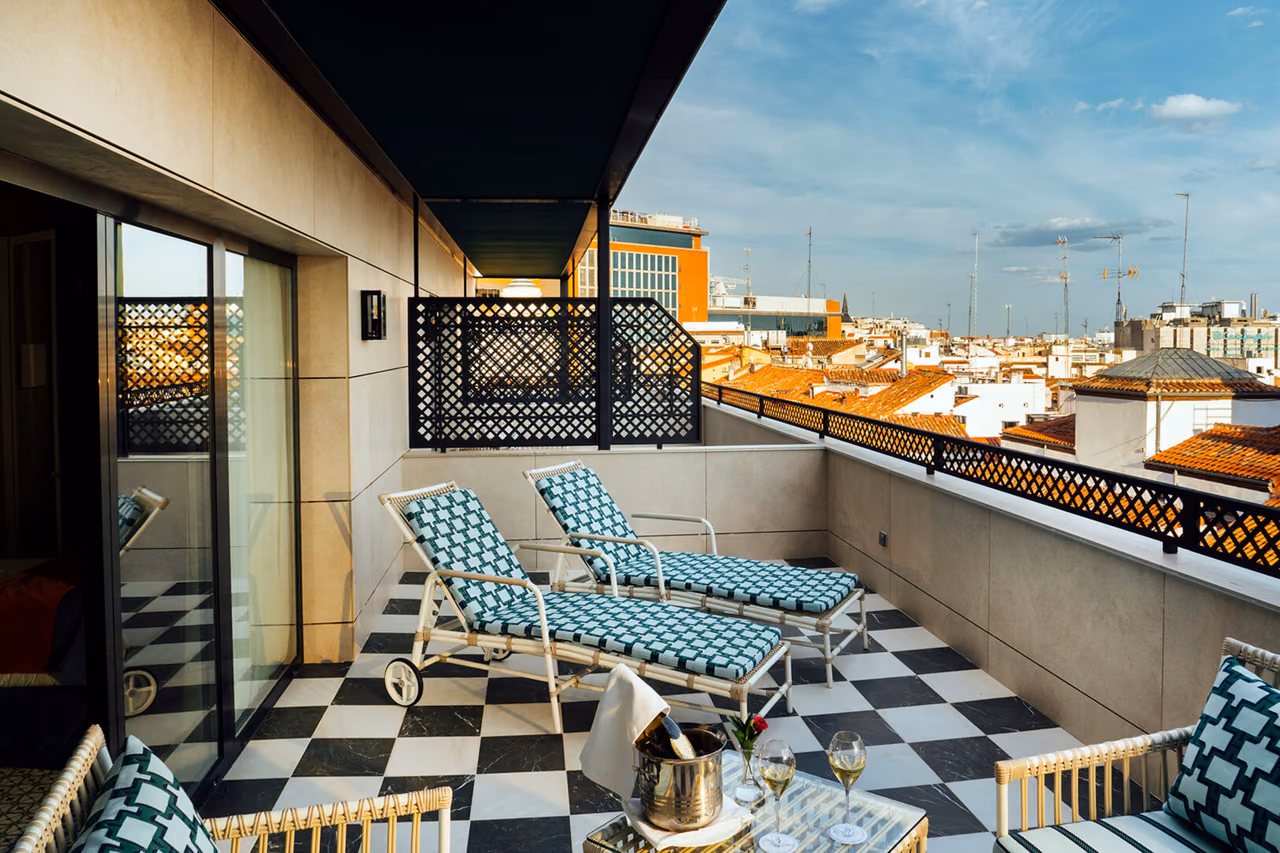 Preciados Room terrace with teal loungers on a black and white checkered floor, champagne on ice and Madrid rooftops beyond