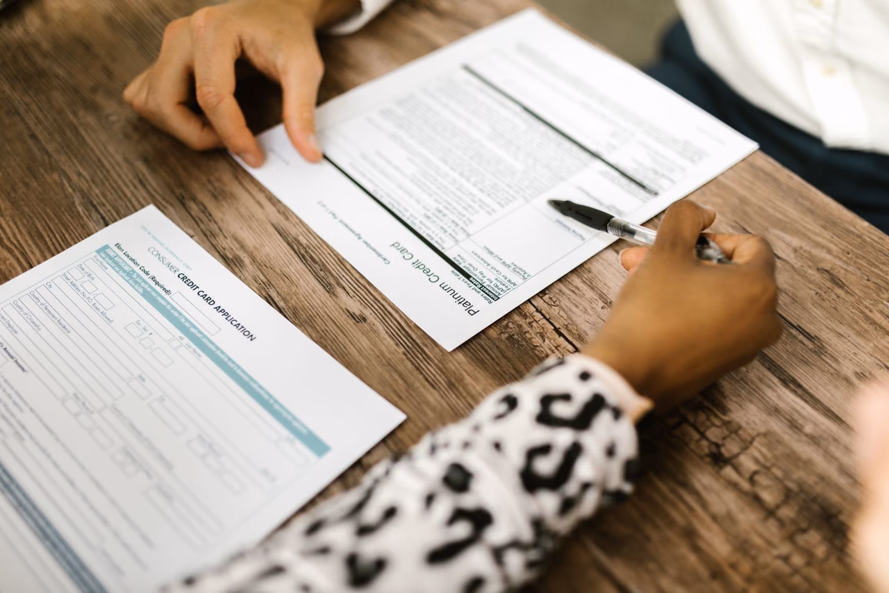 Two people filling out a credit card application at a wooden table