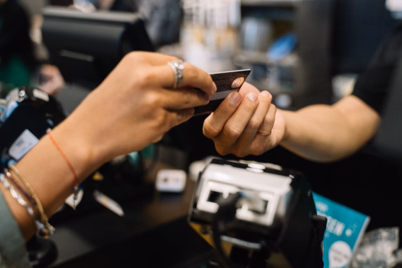 Hands completing a payment with a bank card at a retail checkout counter