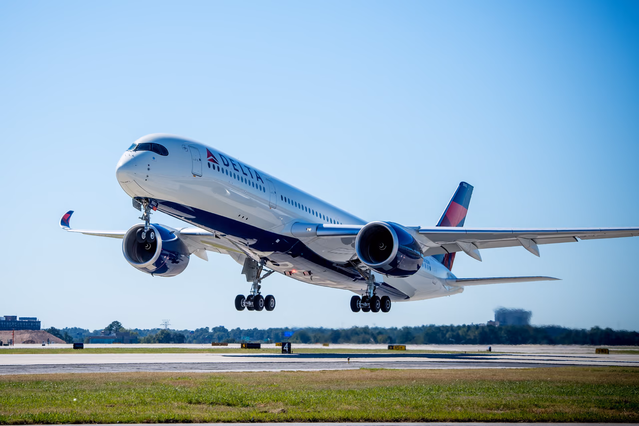 Delta Air Lines Airbus A350-900 lifting off a runway with its landing gear down under a clear blue sky