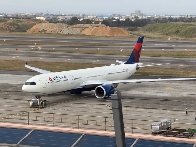 A Delta Air Lines widebody jet taxiing at Taiwan Taoyuan International Airport with a tug at its nose