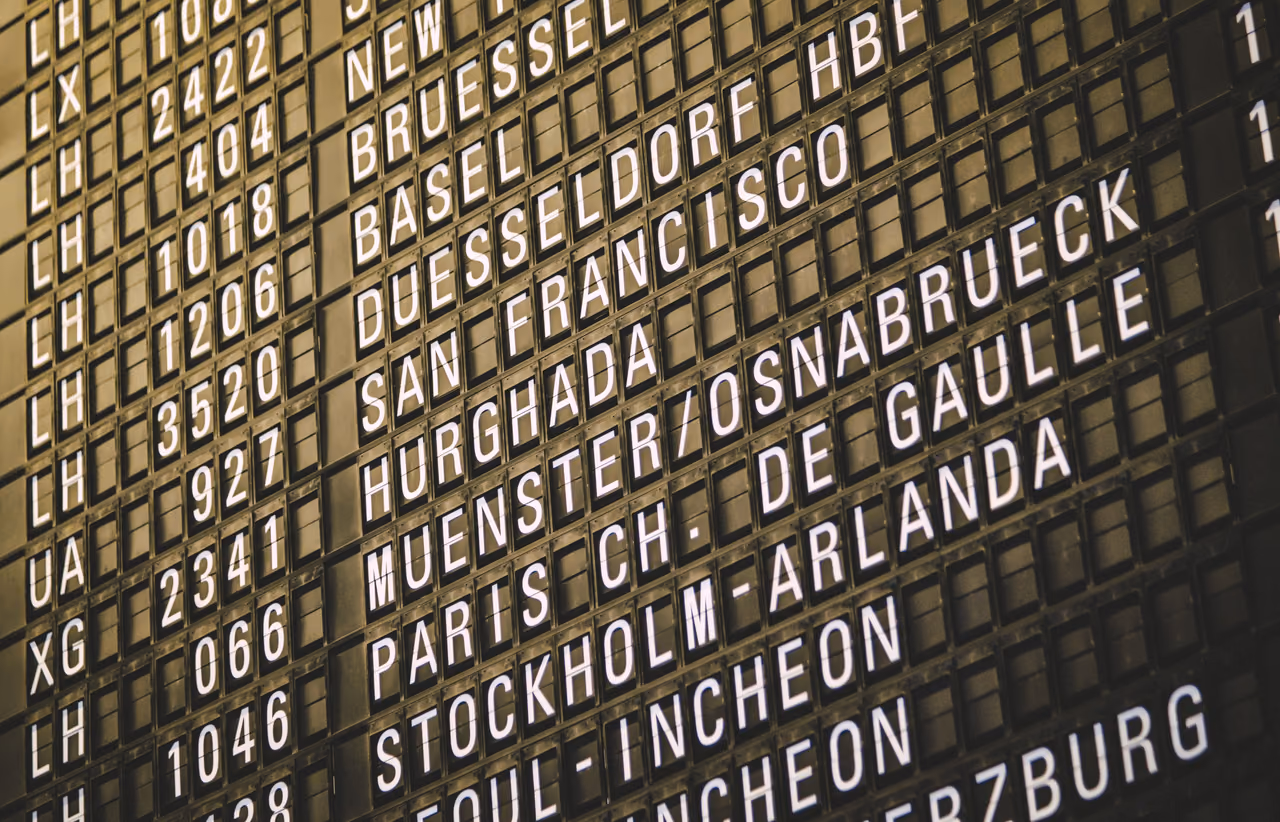 A close view of a split-flap departures board listing flights to San Francisco, Paris, Stockholm, Seoul and other cities.