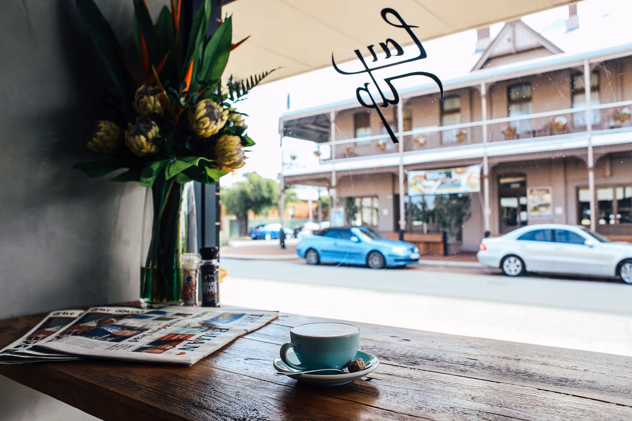 Cup of coffee on a cafe window counter with a view of cars parked on the street outside