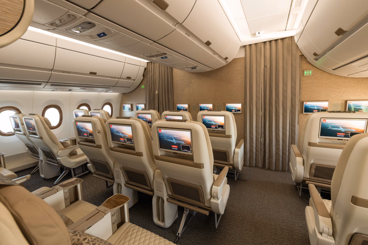 Rear view of Emirates A350 Premium Economy seats, each seatback fitted with a personal entertainment screen, with curtains dividing the cabin ahead