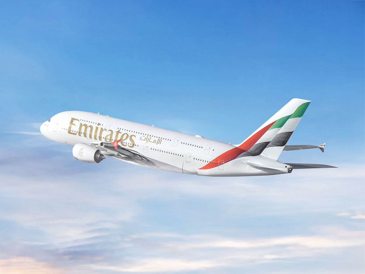 An Emirates Airbus A380 in the airline's white livery climbing through a blue sky with thin clouds