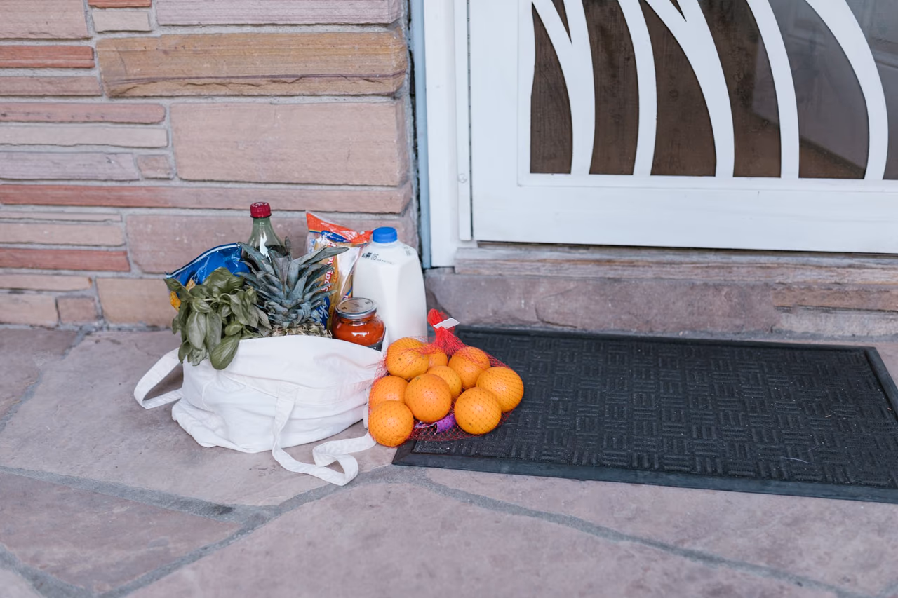 Reusable bag of groceries and fruit left on a doorstep