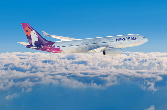 Hawaiian Airlines Airbus A330 with a purple hibiscus tail flying above a layer of white clouds under a clear blue sky
