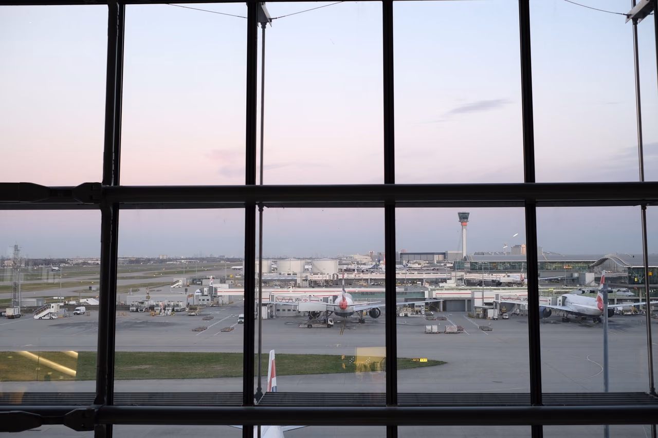 Airplanes on the tarmac seen through an airport terminal window at twilight