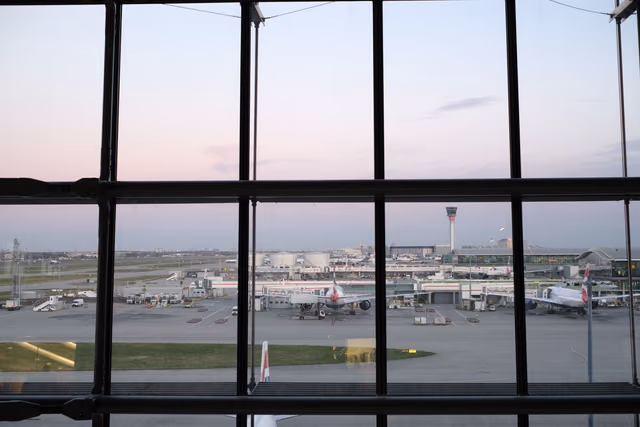 Airplanes on the tarmac seen through an airport terminal window at twilight