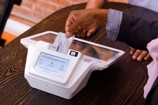 A close-up of a hand inserting a credit card into a countertop card reader at a shop counter
