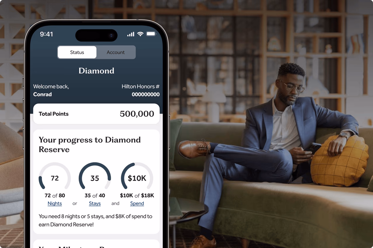 The Hilton Honors app on a phone showing a Diamond member's total points balance and progress toward the next tier, beside a man on a green sofa checking his phone