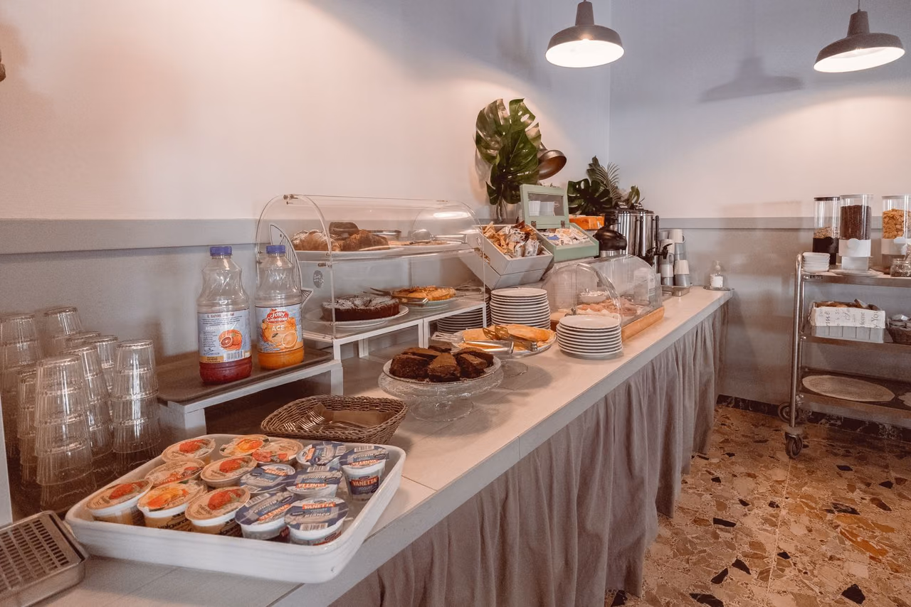 A hotel breakfast buffet with pastries, cereals and juices on a white counter