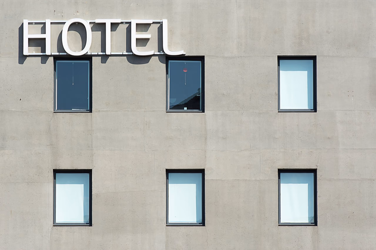 A gray concrete hotel facade with a white HOTEL sign above rows of square windows